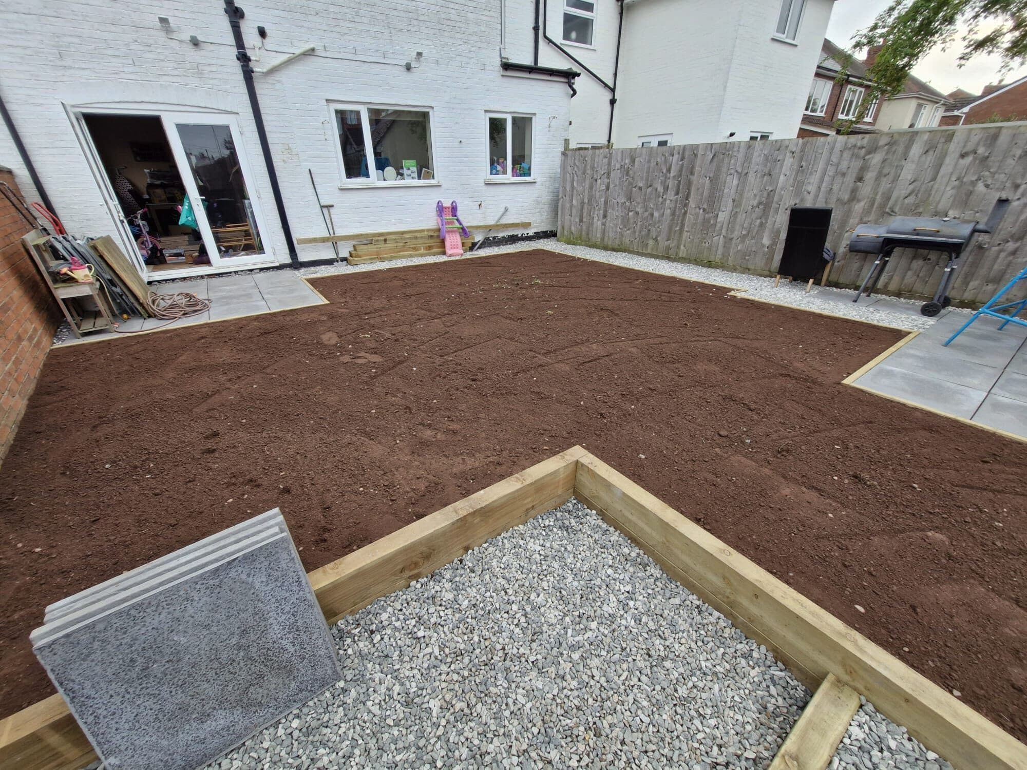 A garden part-way through re-landscaping, with new sleeper edging, gravel and levelled ground ready for turf